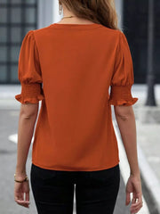 Terracotta blouse with puffed sleeves and smocked cuffs, V-neck detail visible from back.