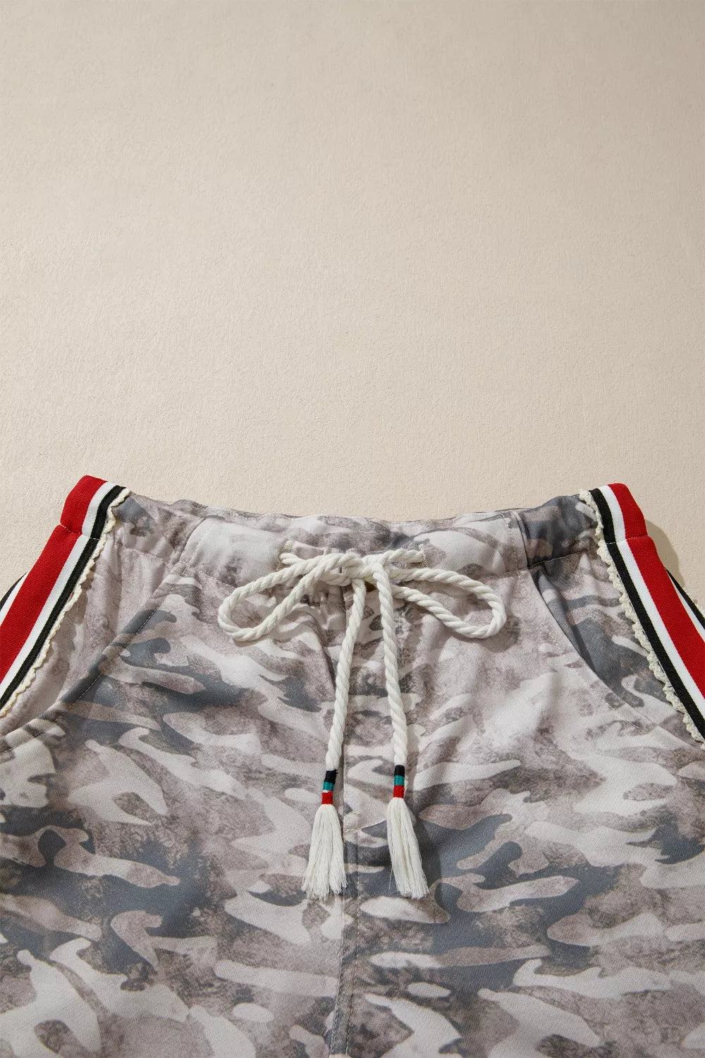 Maternity camo print relaxed fit pants with drawstring and red stripe detail.