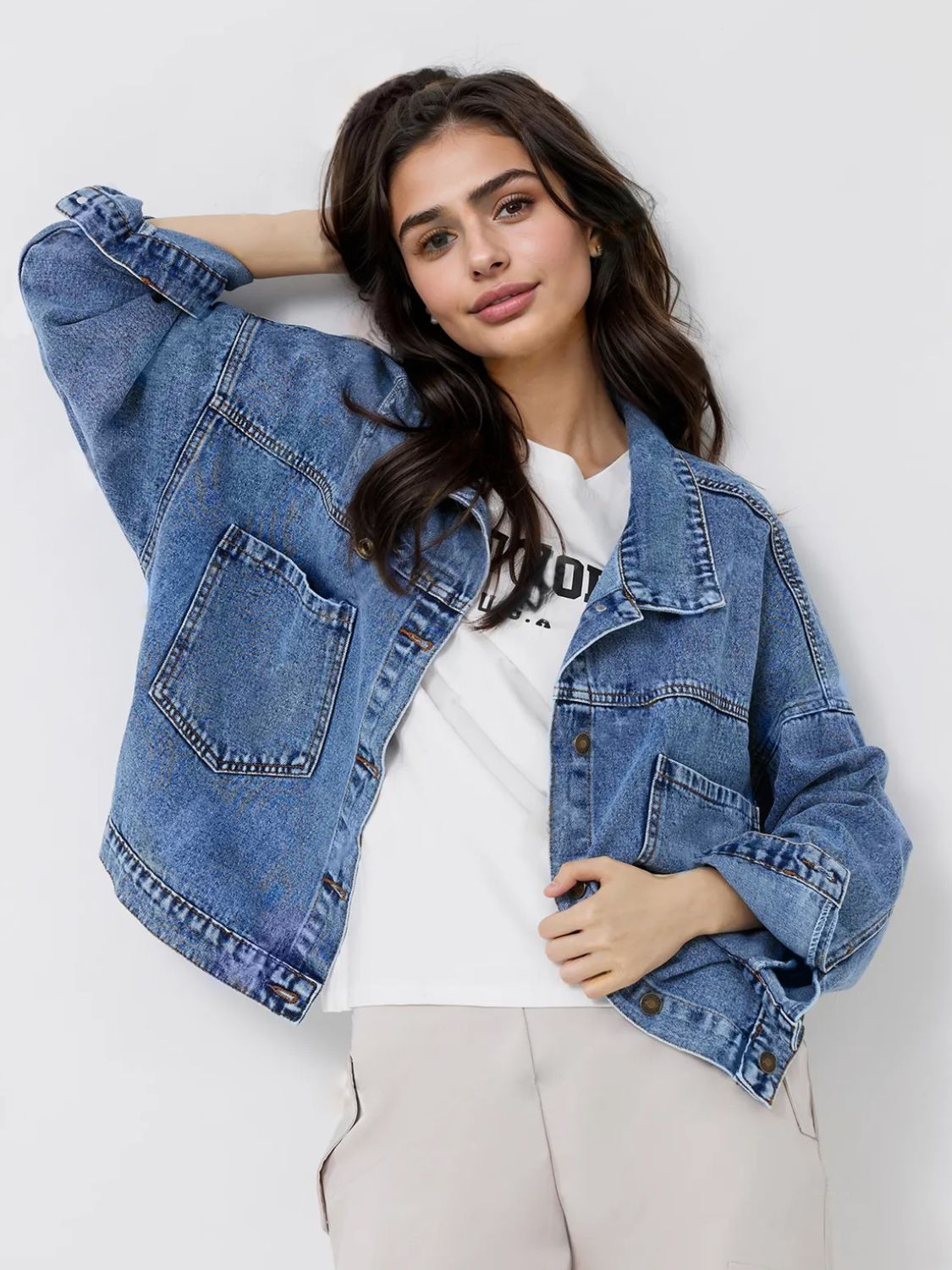 Medium wash denim trucker jacket with button closure and chest pockets.