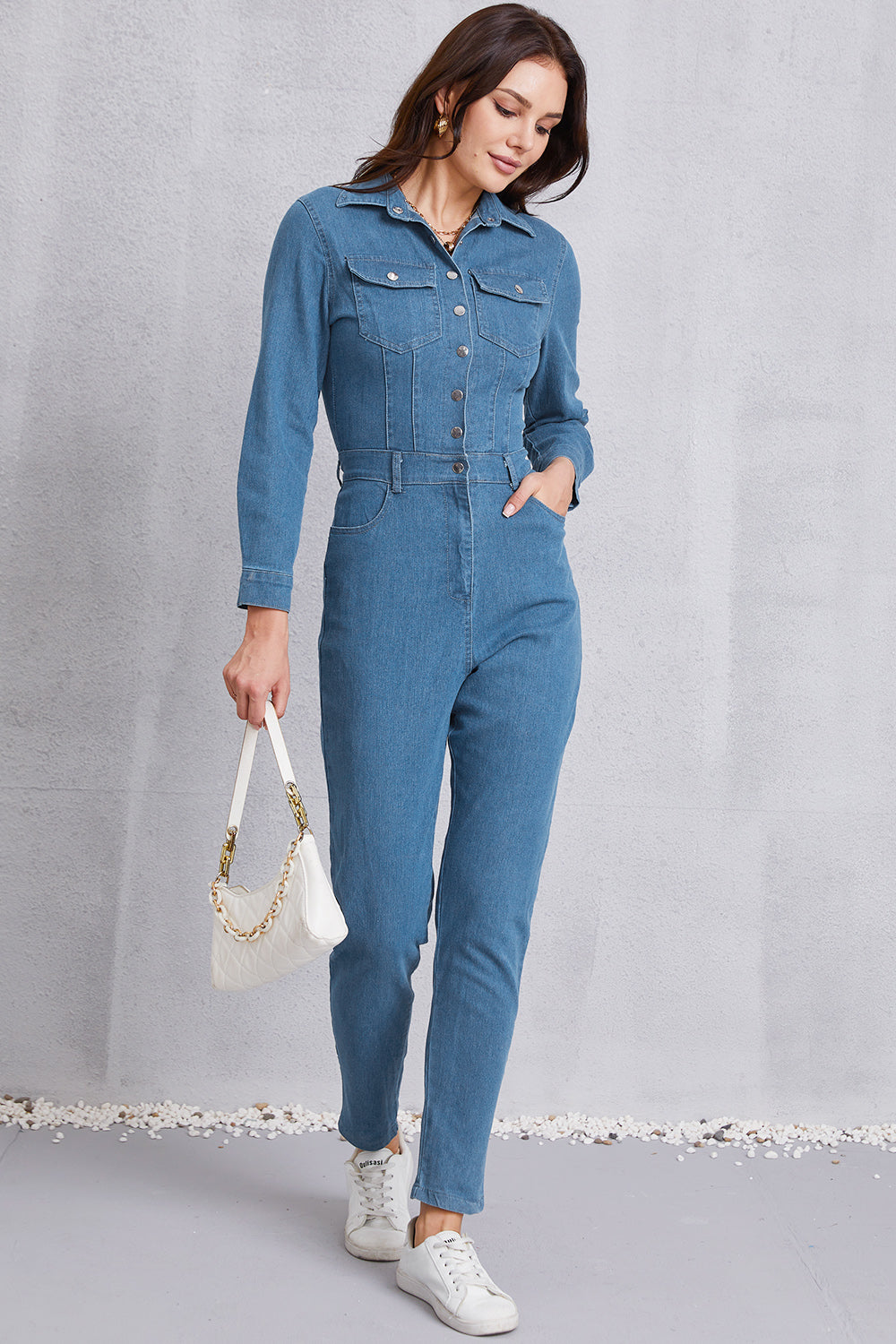Denim utility jumpsuit in medium wash with defined waist, button front, and chest pockets.
