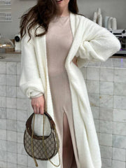 White plush maxi cardigan with balloon sleeves and open front, worn over a tan dress.