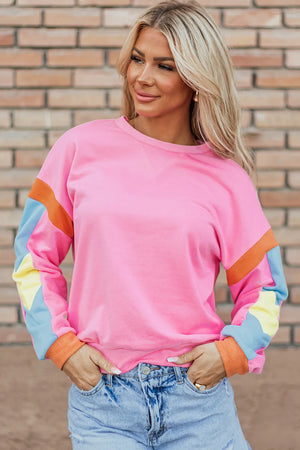 Colorblock sleeve crewneck sweatshirt in fuchsia pink with orange, light blue, and yellow colorblock sleeves.