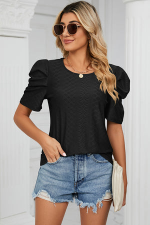 Black perforated puff sleeve top with textured pattern, paired with denim shorts.
