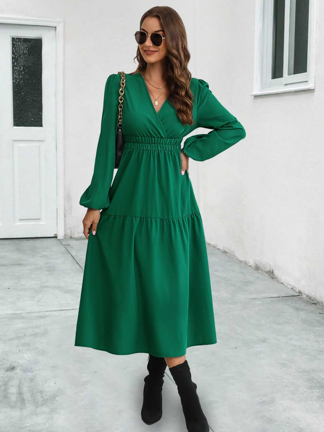 Dark green tiered midi dress with V-neck, long sleeves, and gathered waistline.
