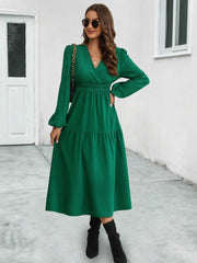 Dark green tiered midi dress with V-neck, long sleeves, and gathered waistline.