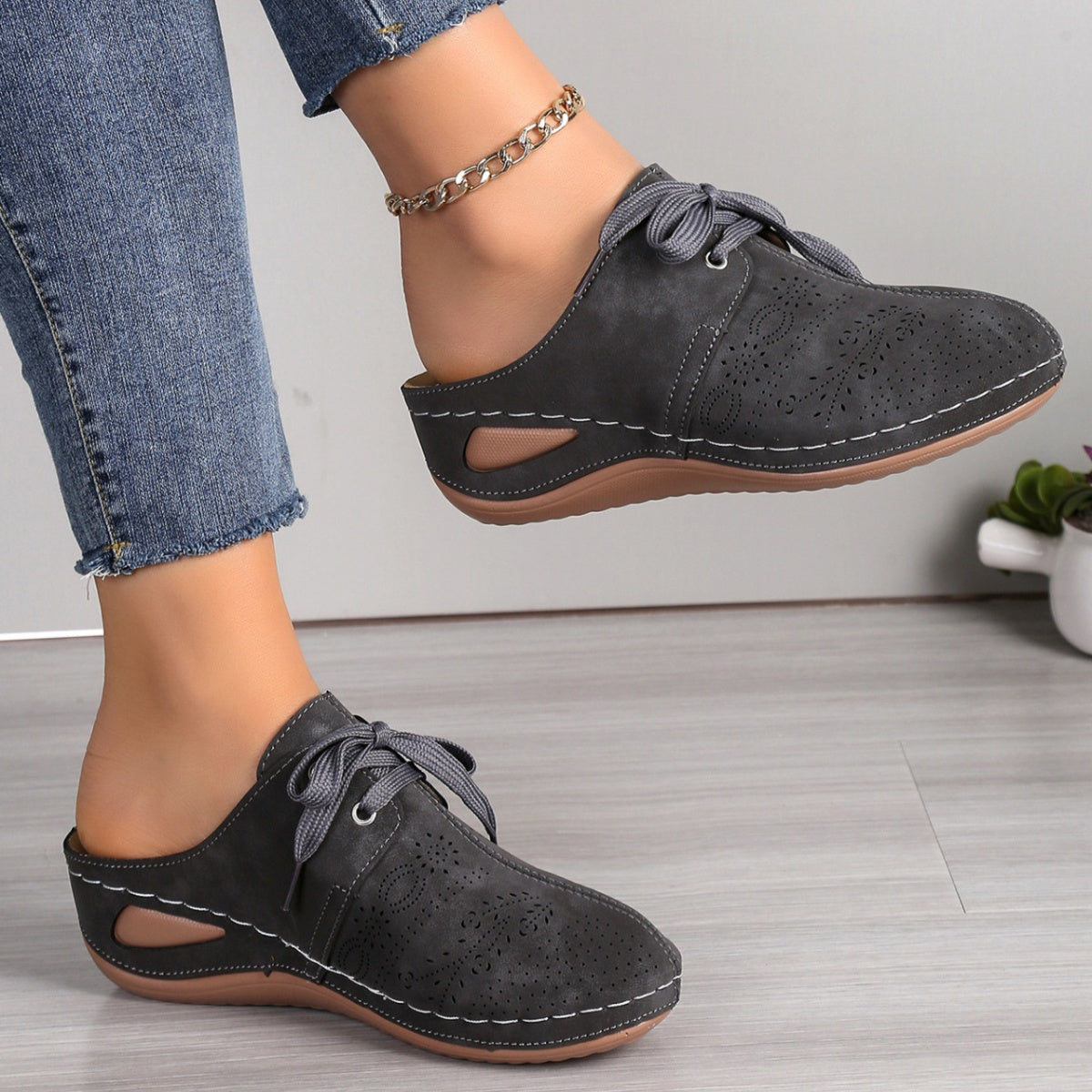 Dark gray perforated slip-on mules with lace-up detail and cut-out sides.