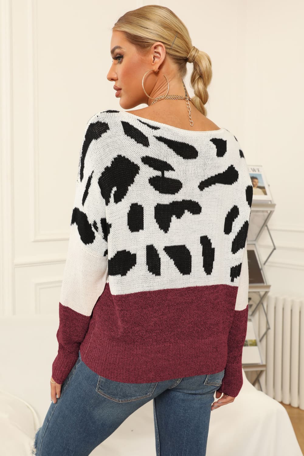 Cow print knit sweater with boat neck and burgundy hem.