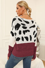 Cow print knit sweater with boat neck and burgundy hem.
