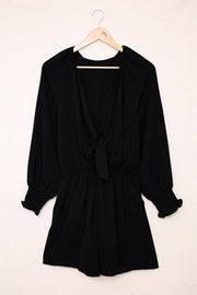 Black tie-front blouson sleeve playsuit with cinched waist and ruffled cuffs.