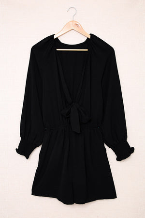 Black tie-front blouson sleeve playsuit with cinched waist and ruffled cuffs.