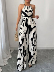 Chic abstract print halter jumpsuit in black and white, featuring wide legs and a tie waist.