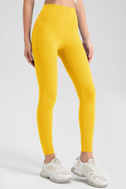 Yellow high-waist performance leggings with sculpting seams and a full-length cut.