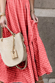 Red gingham smocked maxi dress with flutter sleeves and tiered skirt detail.