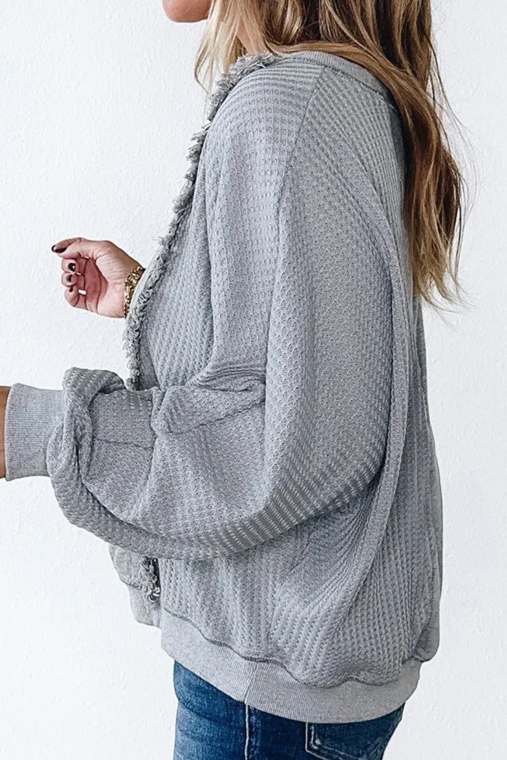 Gray waffle knit top with fringe trim and cuffed sleeves.