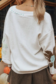 White knit sweater with embroidered floral details on sleeves and neckline