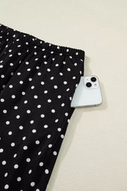 Black polka dot maternity wide-leg pants with a side pocket holding a smartphone.