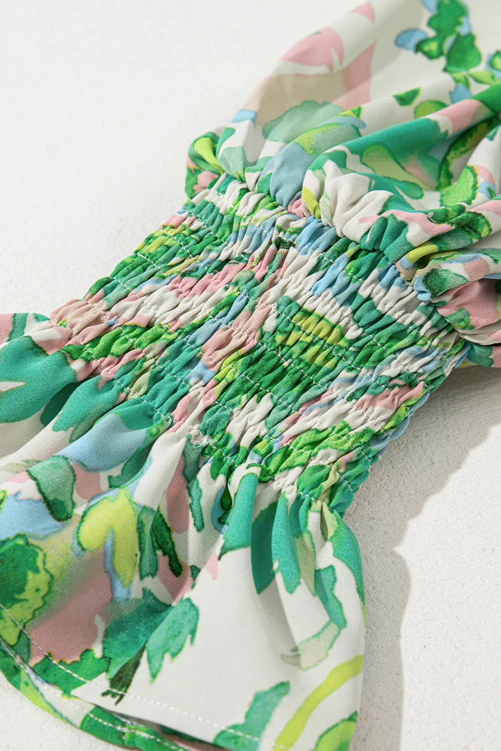 Smocked yoke blouse in green floral print with voluminous sleeves.