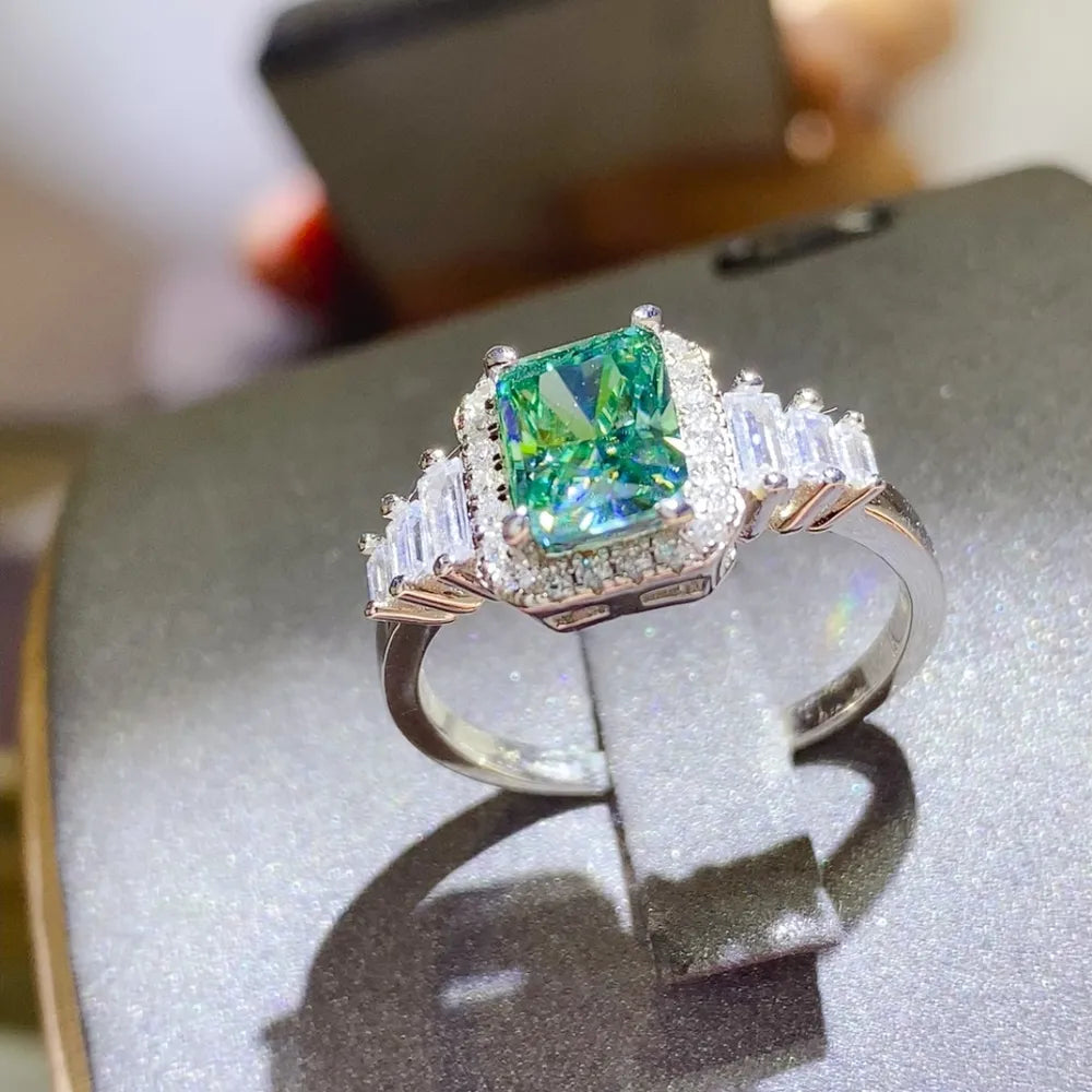 Emerald-cut moissanite halo ring in silver with baguette and round accent stones.