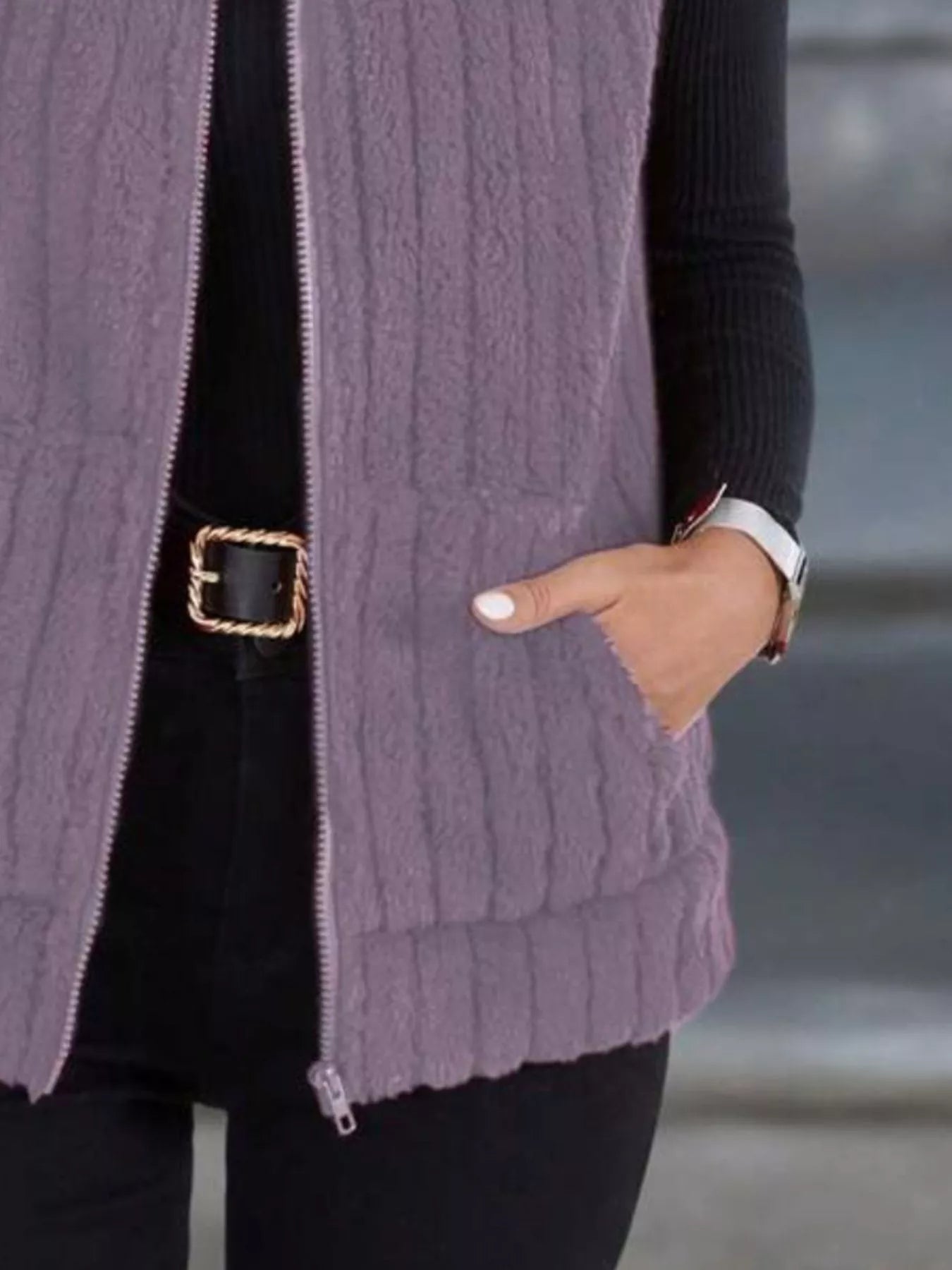 Purple fleece zip-up vest with textured stripes and pockets, worn over black clothing.