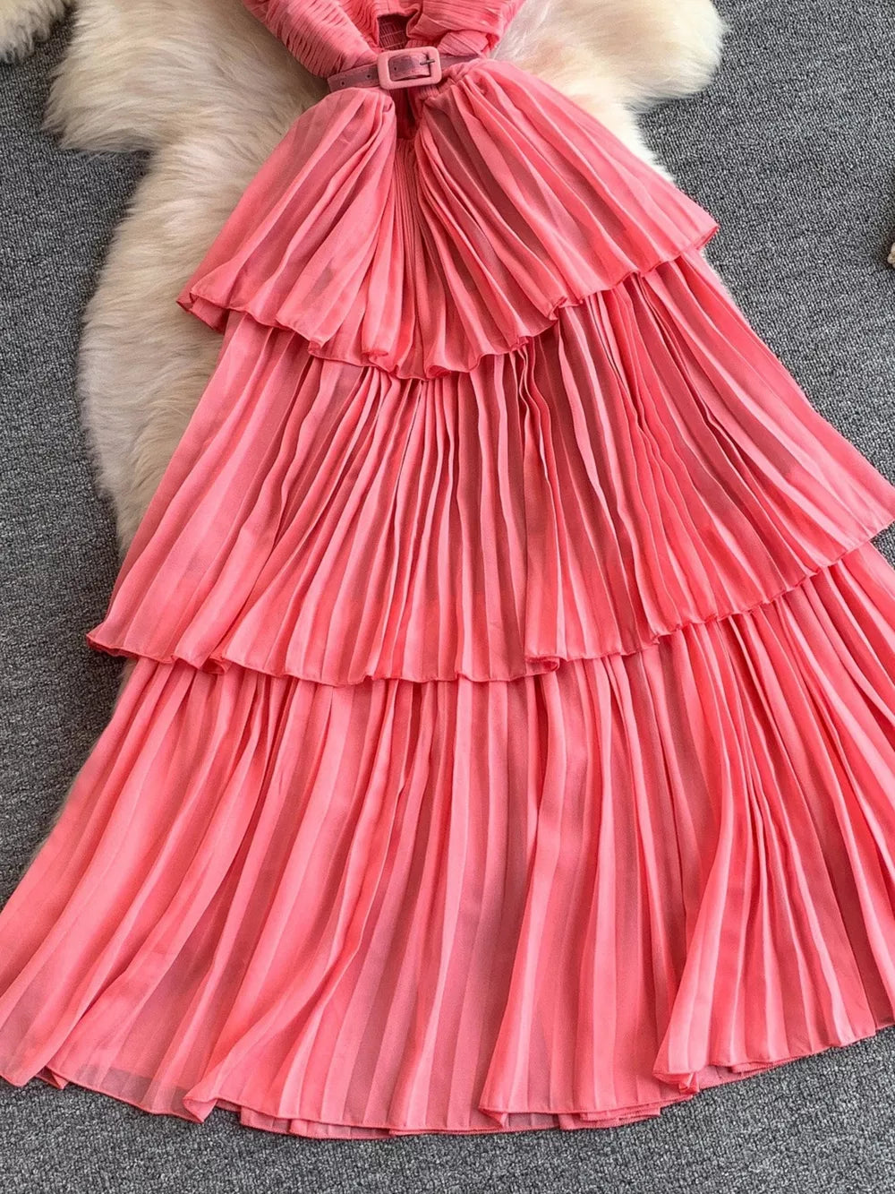 Pink belted midi dress with tiered pleated skirt and spaghetti straps.