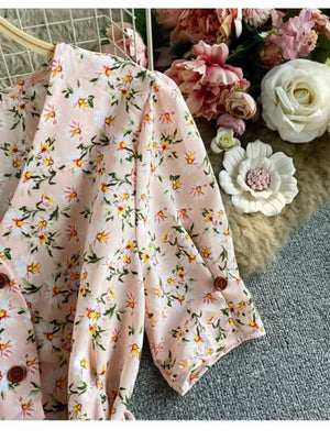 Pink floral v-neck midi dress with button details and a belted waist.