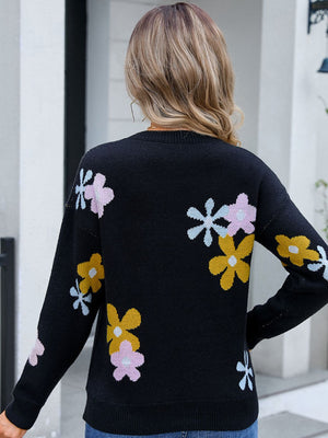 Black crewneck pullover sweater with floral intarsia knit pattern in pink, yellow, and light blue.