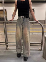 Vintage wash distressed wide-leg jeans with paint splatter detail and a black belt.