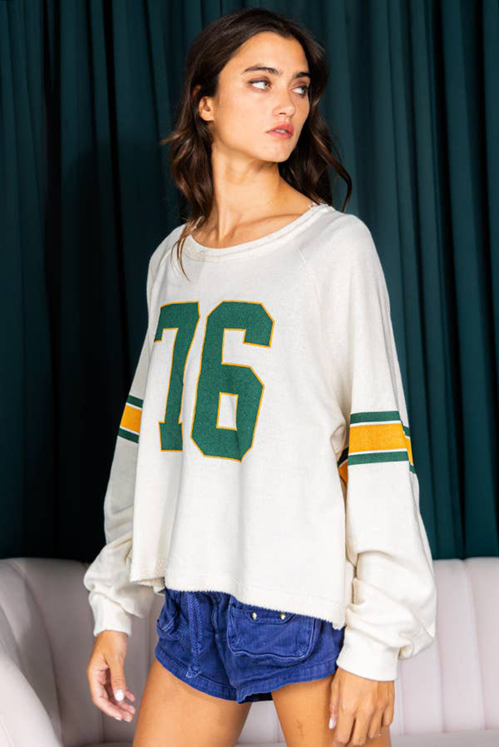 White raglan sleeve sweatshirt with green "76" graphic and striped sleeves