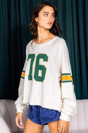 White raglan sleeve sweatshirt with green "76" graphic and striped sleeves