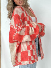 Oversized checkerboard knit cardigan in deep red and beige with balloon sleeves.