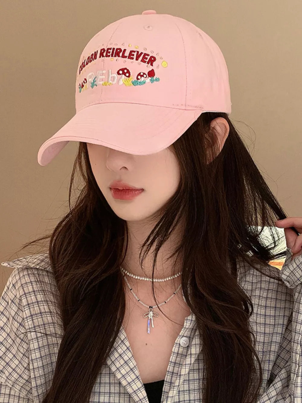 Blush pink baseball cap with playful mushroom embroidery and text detail.