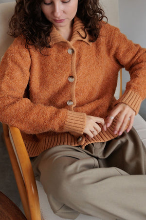 Textured bouclé collar cardigan in tangerine with button front and ribbed cuffs.