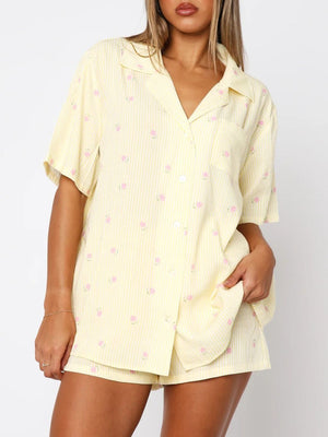 Pastel yellow striped pajama set with pink floral print, collared button-up shirt and shorts.