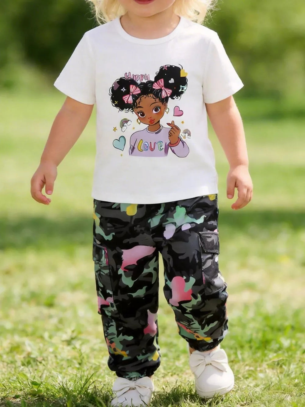 White cartoon graphic t-shirt and multi-color camo cargo pants set for girls.