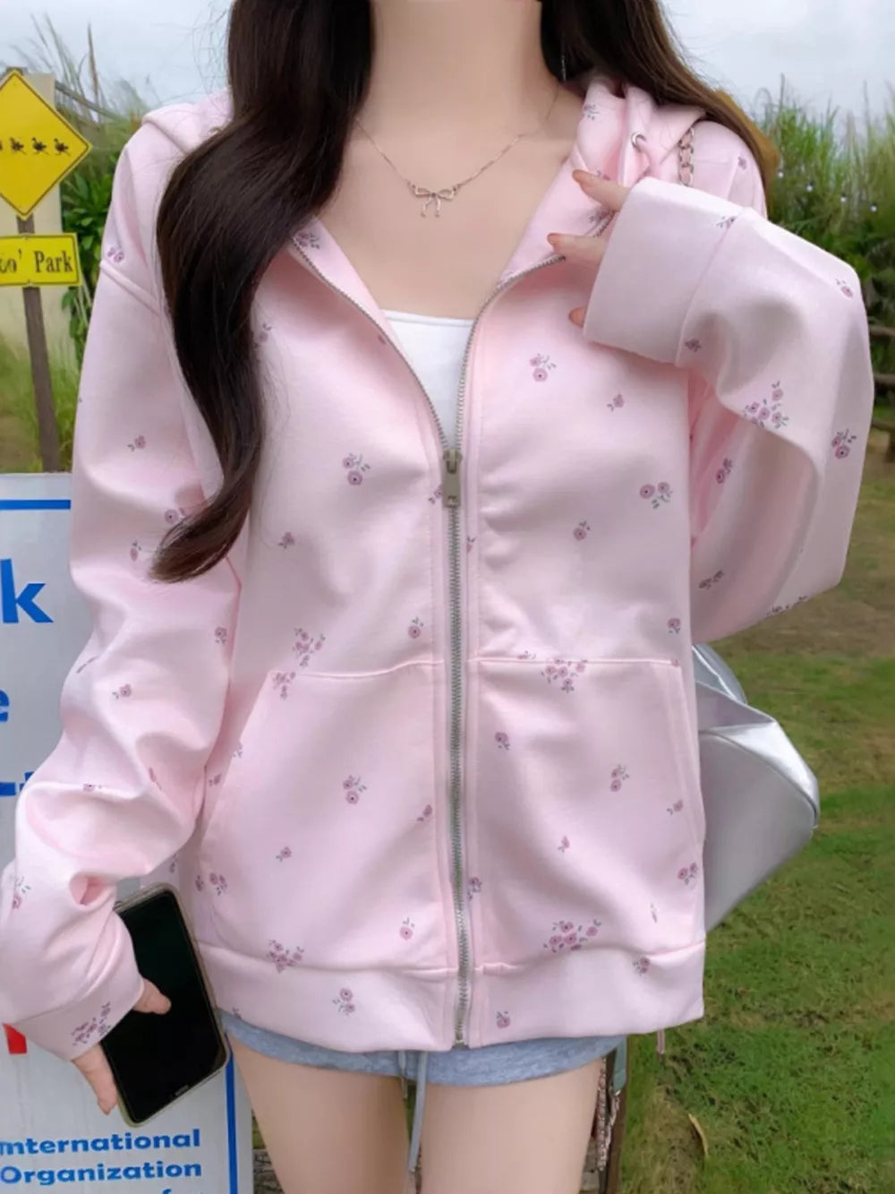 Pink floral zip-up hoodie with drawstring and pockets.