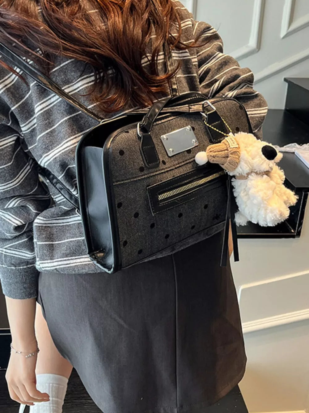 Sophisticated black polka dot shoulder bag with a plush toy charm.