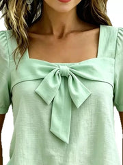 Light green puff sleeve shirt with a large bow tie detail on a square neckline.