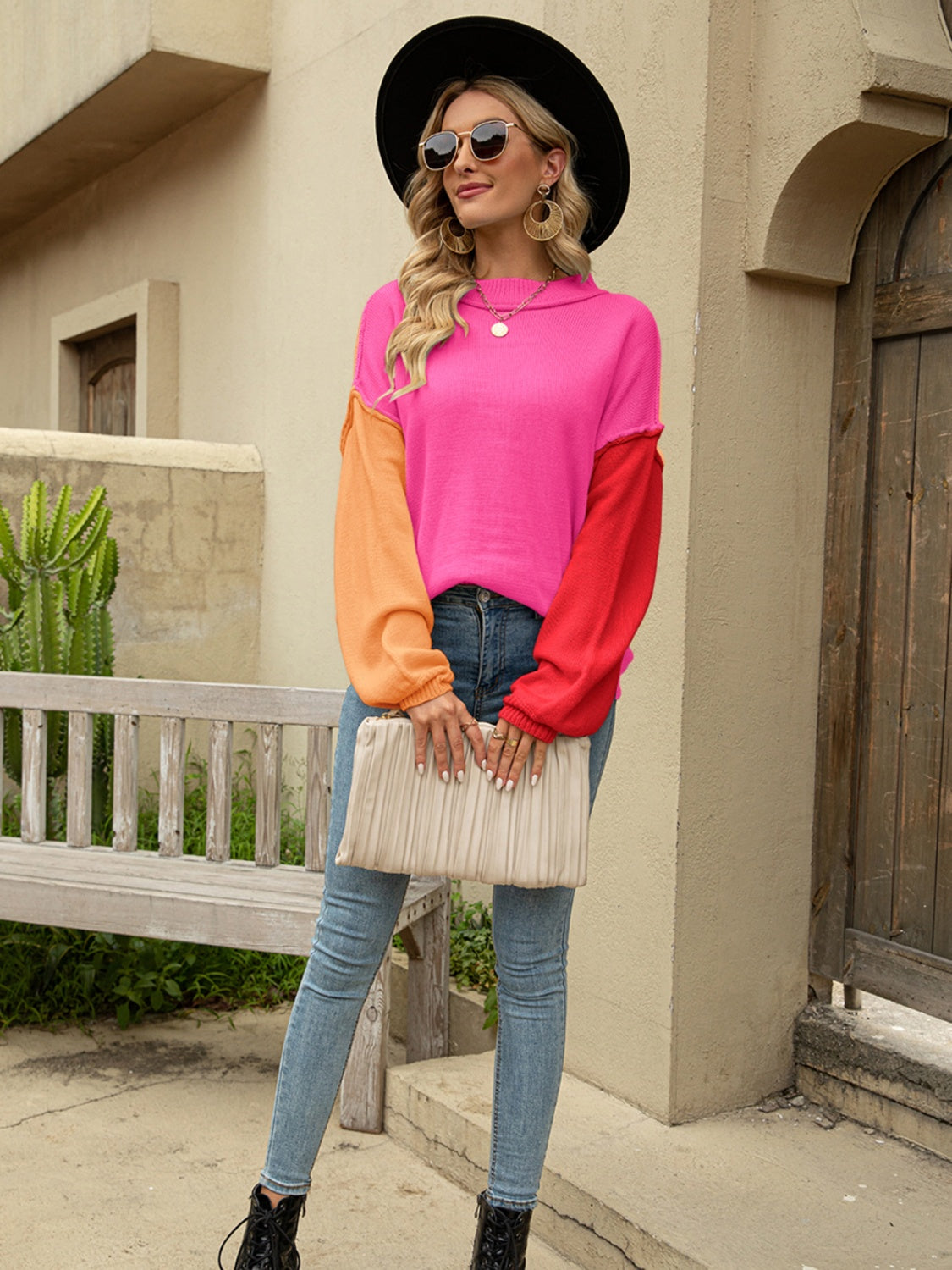 Colorblock drop shoulder knit sweater with pink, orange, and red sleeves.