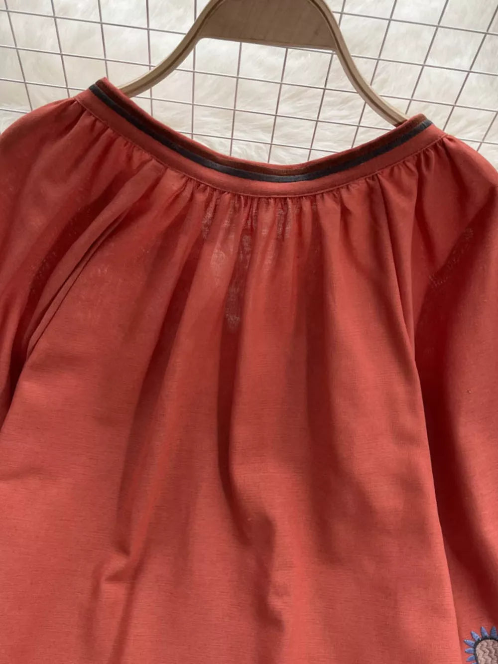Apricot tie neck blouse with billowy sleeves and embroidered detail.