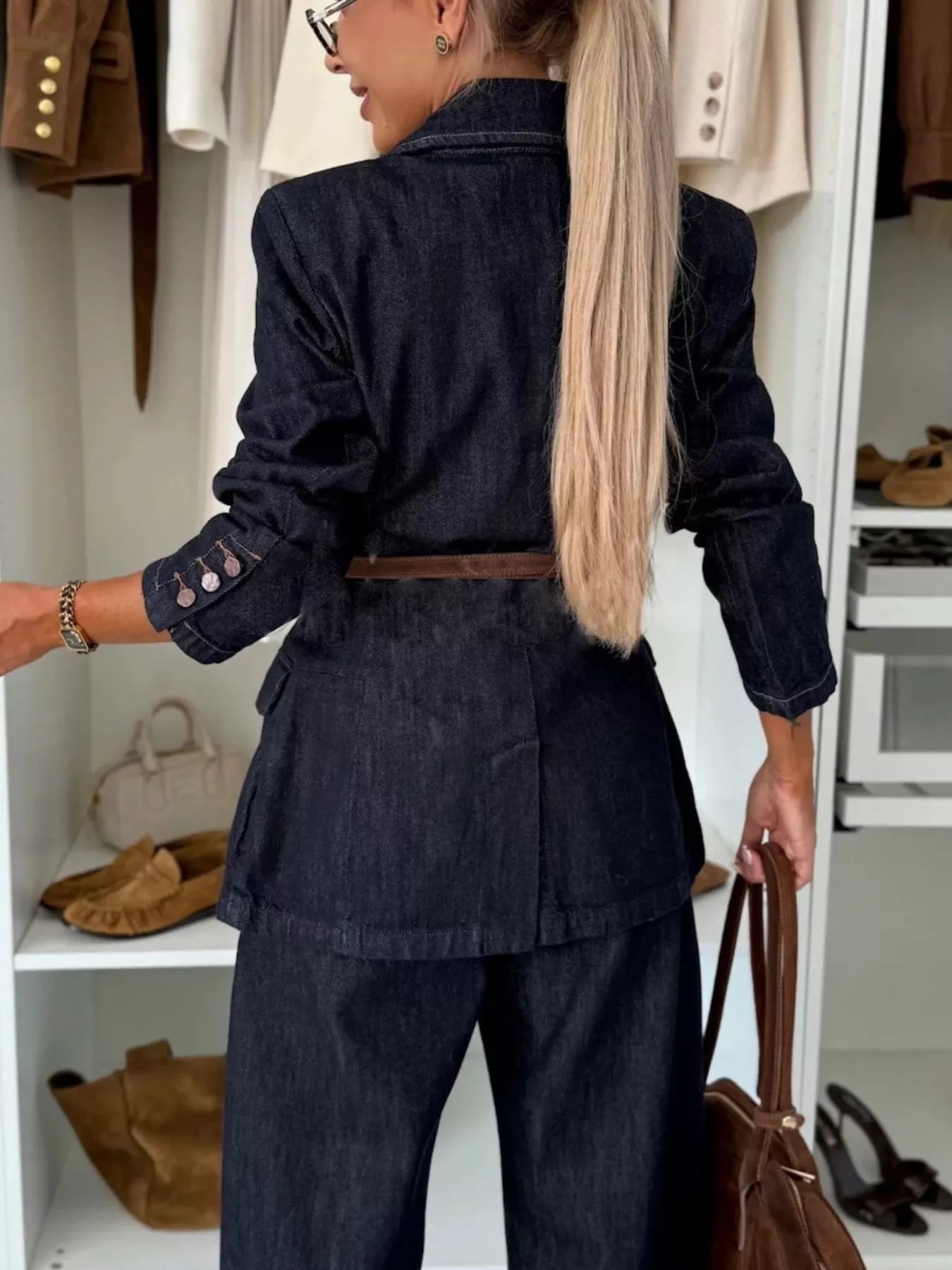 Dark navy denim blazer with a belted waist and buttoned cuffs, styled with matching trousers.