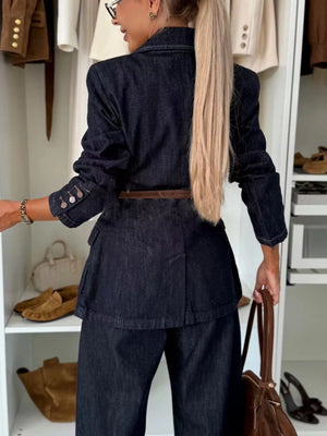 Dark navy denim blazer with a belted waist and buttoned cuffs, styled with matching trousers.