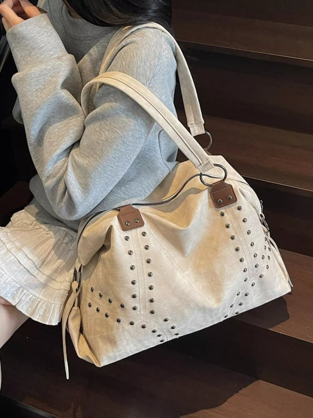 Cream white trapezoid handbag with distressed studded detail and brown accents