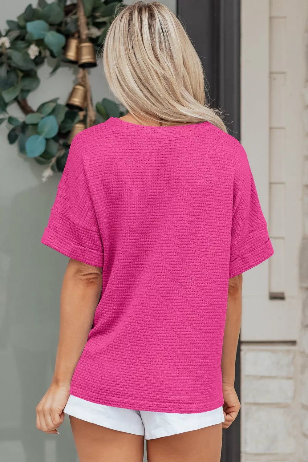 Hot pink waffle knit V-neck t-shirt with cuffed short sleeves.
