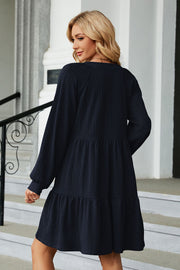 Textured babydoll mini dress in dark blue with voluminous sleeves and tiered hem.