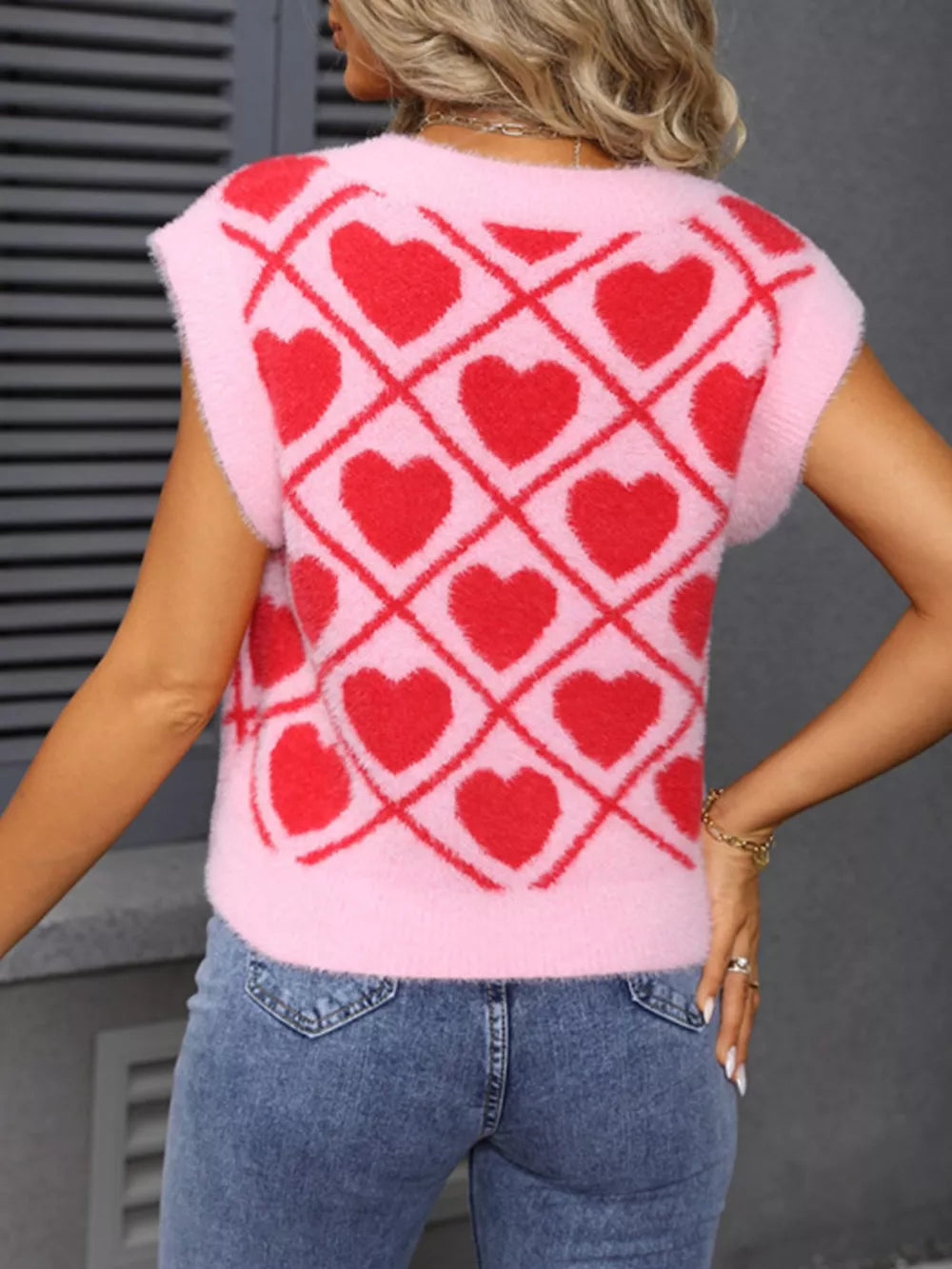 Pink acrylic V-neck sweater vest with red argyle heart pattern.
