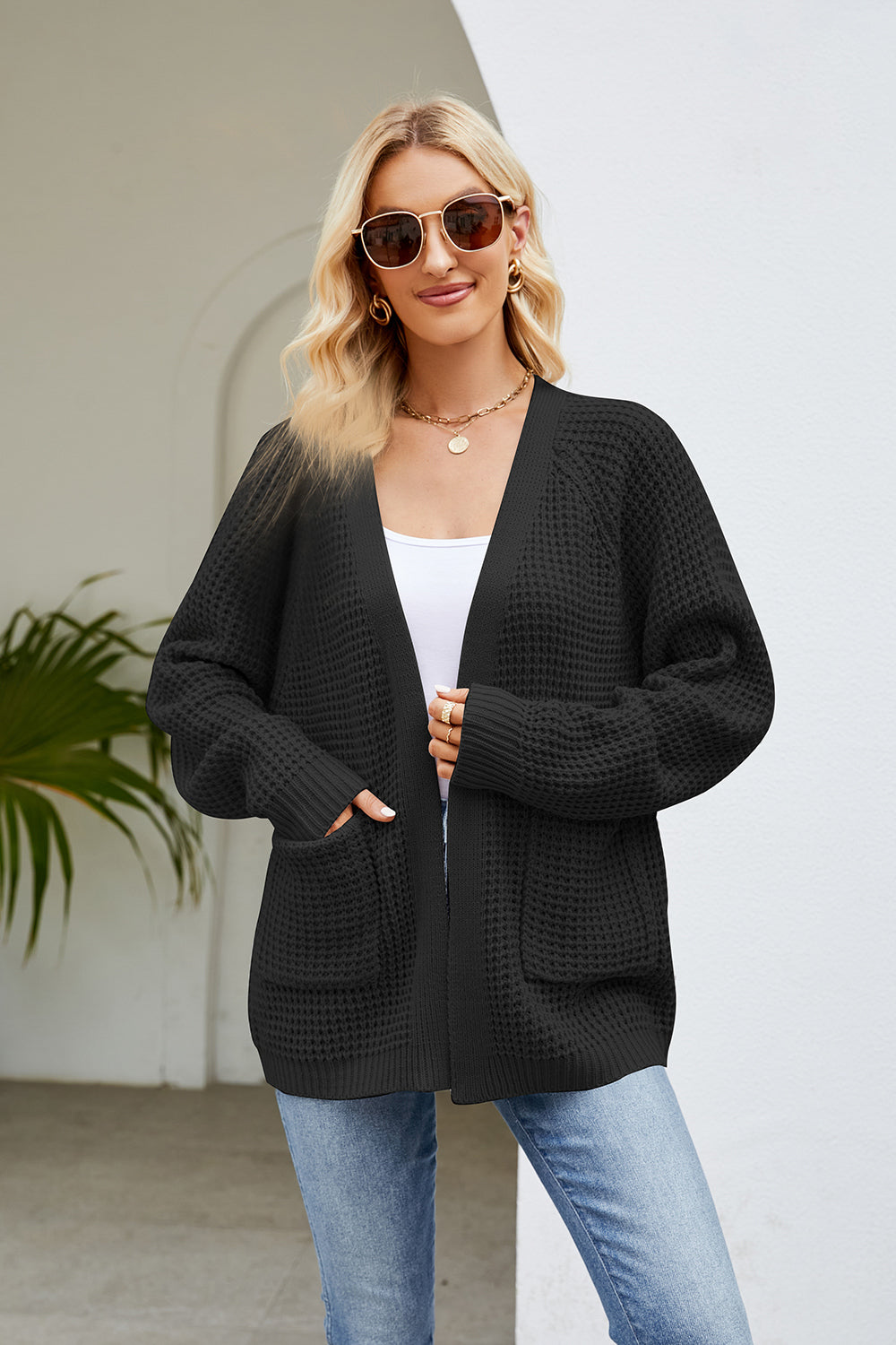 Black waffle knit raglan pocket cardigan with open front and long sleeves.