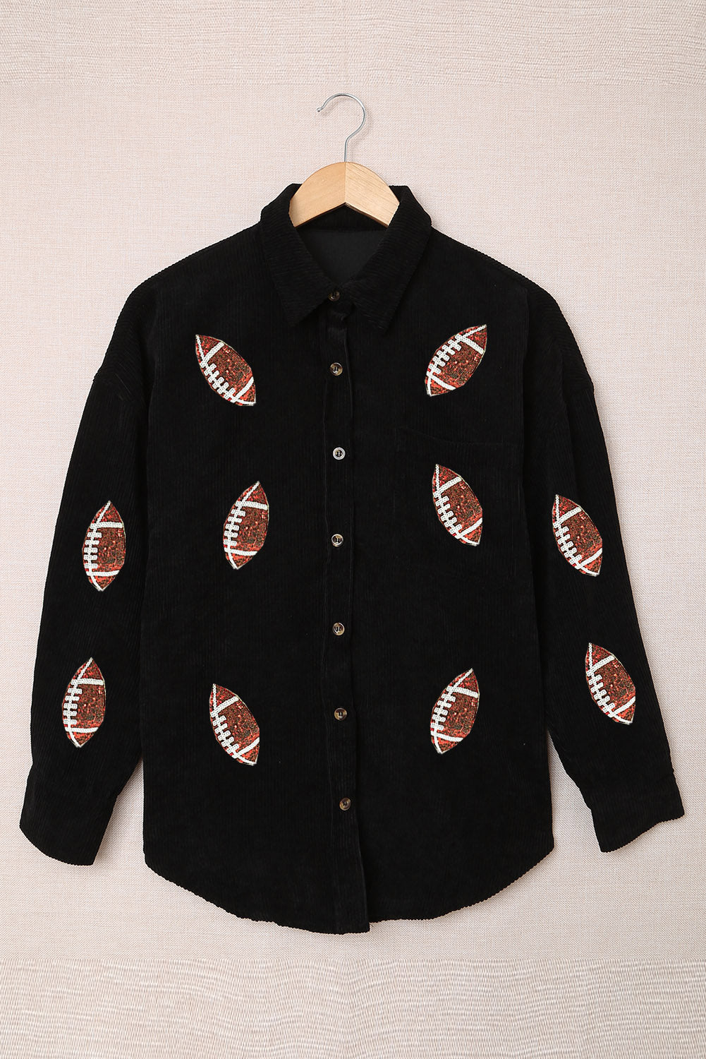 Black corduroy shirt jacket with all-over football print and button front.