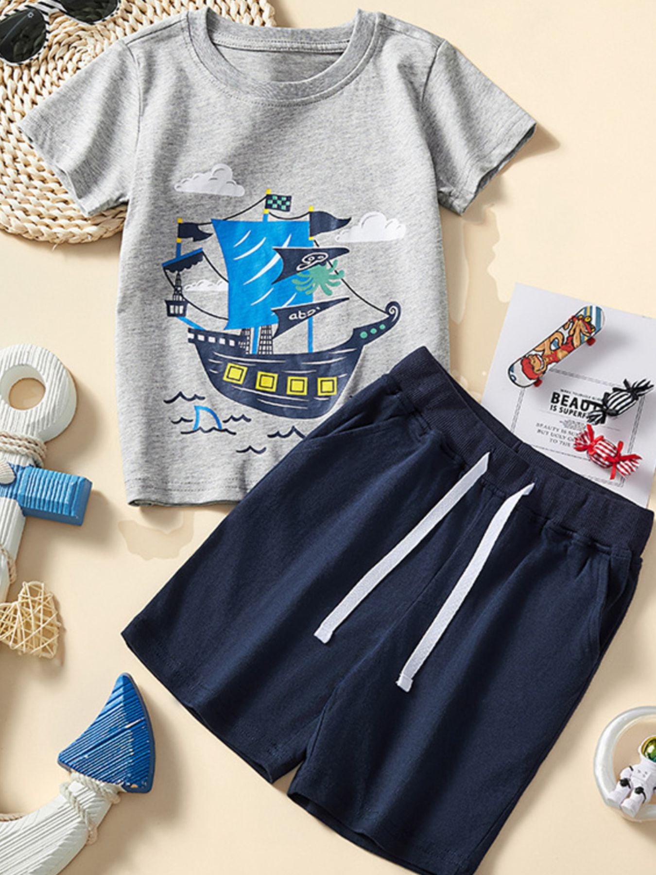Toddler grey cotton tee with sailing ship graphic and navy elastic waist shorts.