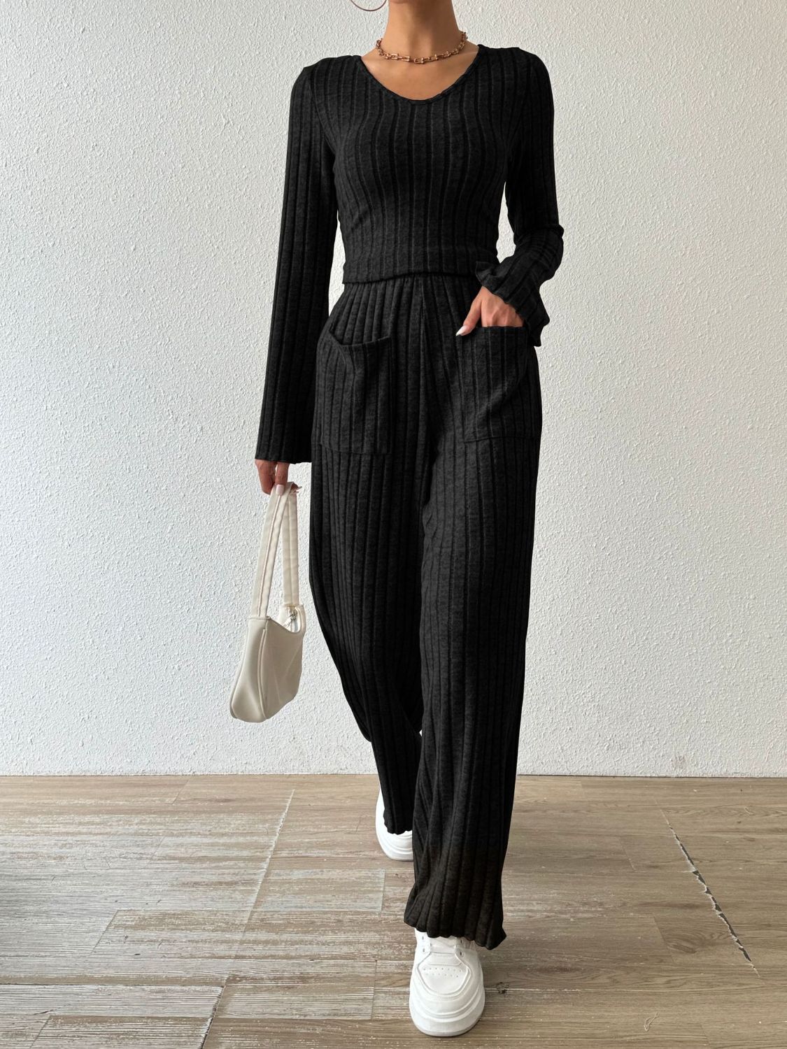 Black ribbed knit loungewear set with flared sleeves and wide-leg pants featuring patch pockets.