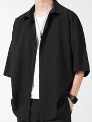 Men's black oversized short sleeve button-up shirt with a white t-shirt underneath.